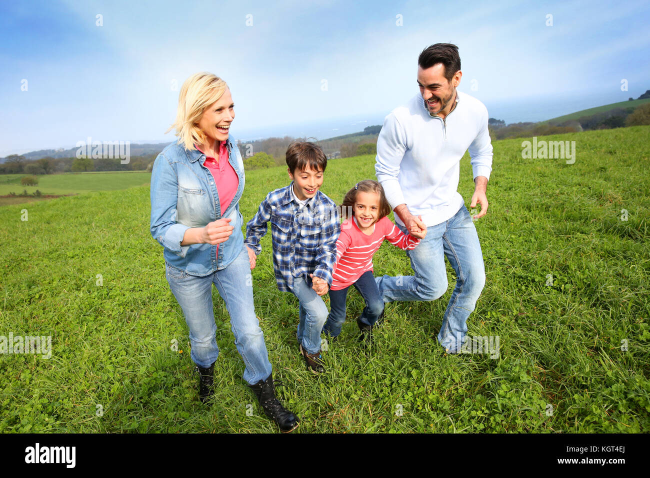 Familie von vier zusammen in natürlicher Landschaft läuft Stockfoto