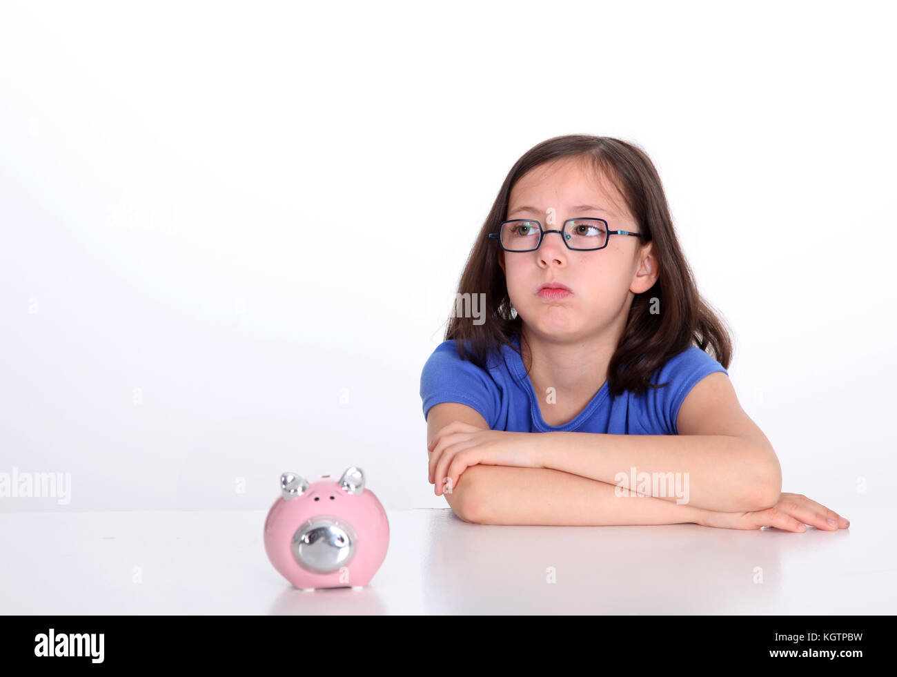 Kleines Mädchen mit gelangweiltem Blick, das bei der Schweinebank sitzt Stockfoto