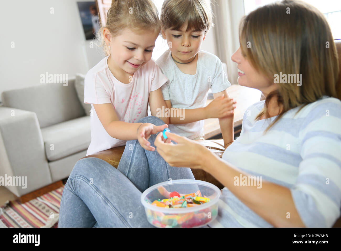 Kinder erhalten Bonbons von ihrer Mutter Stockfoto