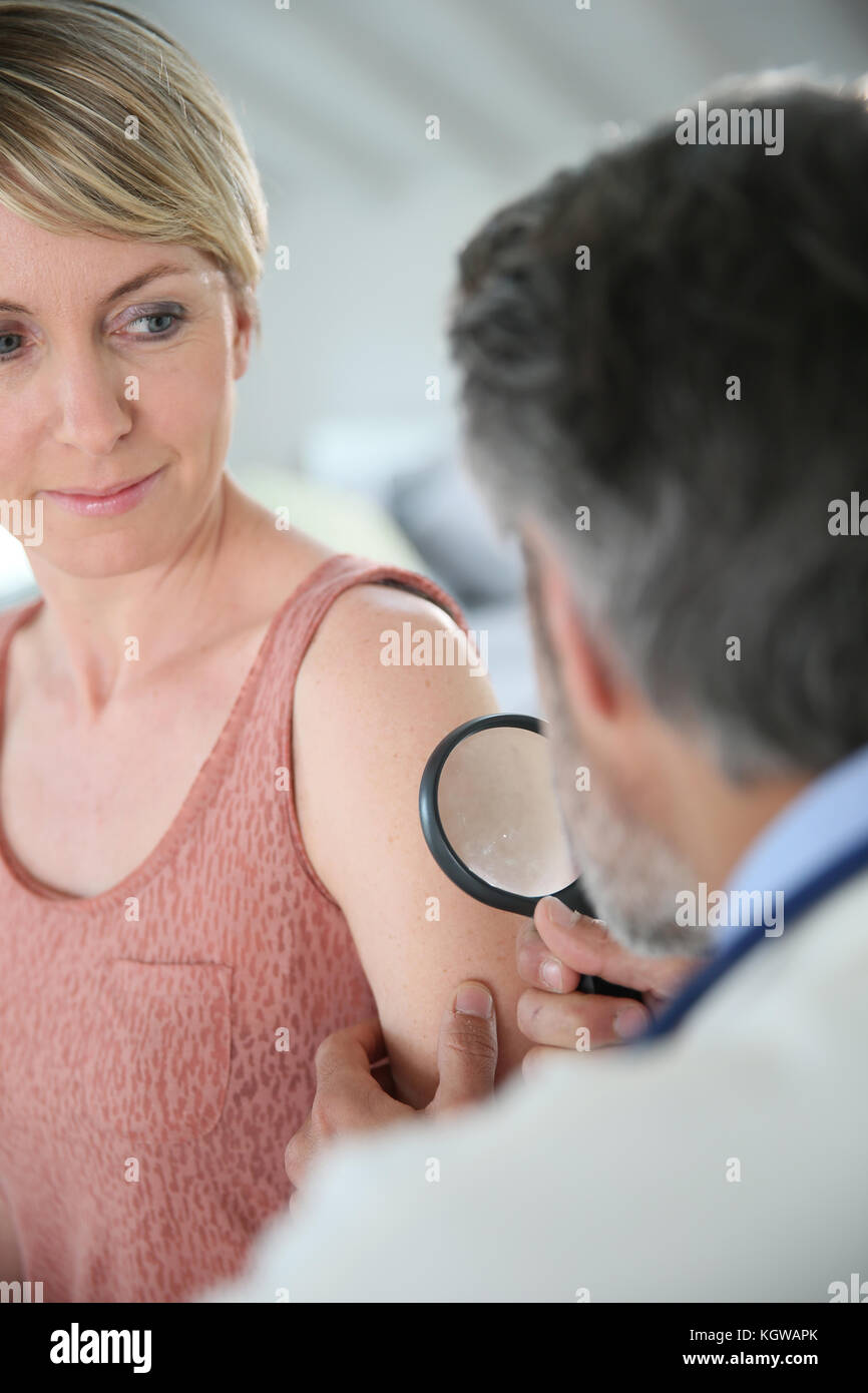 Dermatologe an der Frau Maulwurf mit Lupe suchen Stockfoto