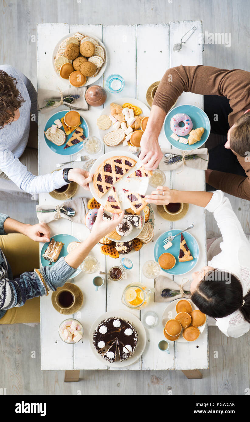 Überblick über eine Gruppe von Freunden, die Scheiben von leckeren runden Kuchen während der festlichen Abendessen Stockfoto