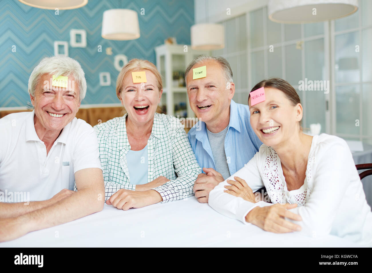 Fröhliche Senioren lachen während der Sitzung durch die Tabelle während Schätze Charakter Spiel Stockfoto