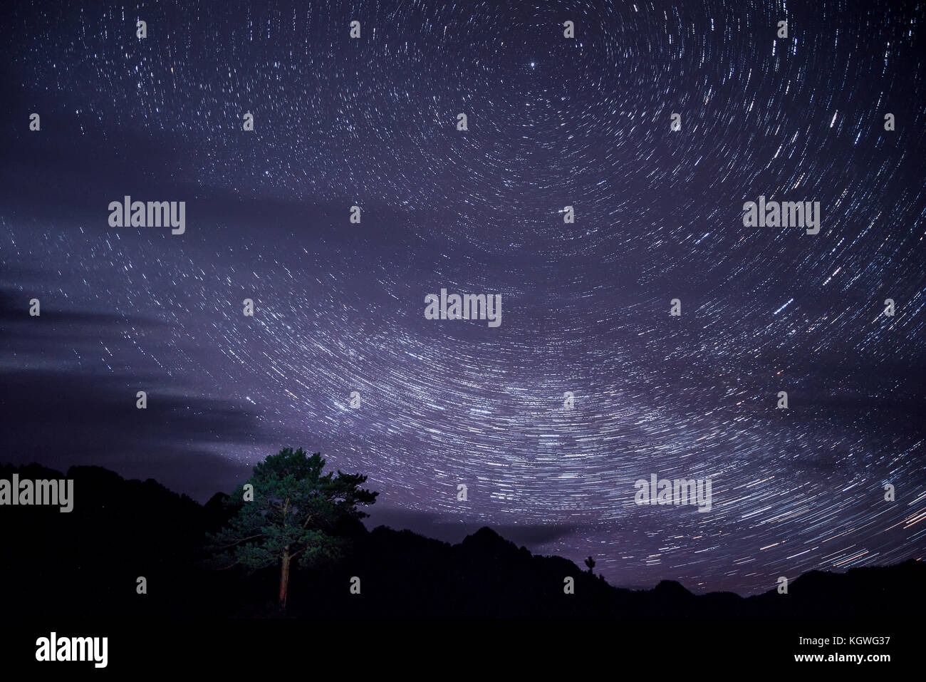 Schöne Nacht Landschaft mit Spuren von Sternen in der Nacht Himmel und Wolken auf dem Hintergrund der dunklen Umrisse der Berge und Kiefer Stockfoto