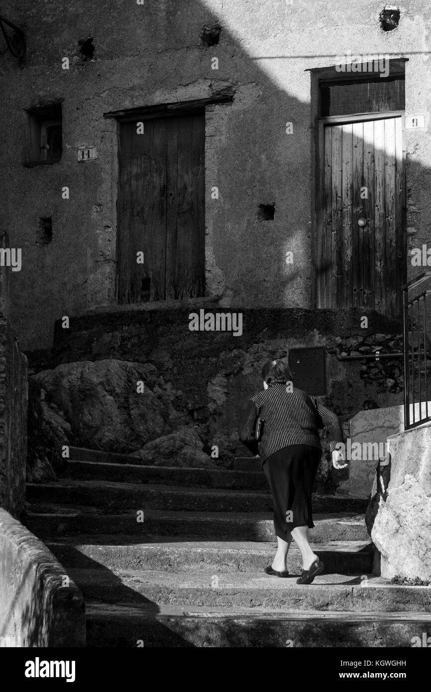 Eine alte Frau geht in die Straßen des Dorfes von aieta, Italien. aieta (auch in ajeta Form geschrieben) ist eine italienische Gemeinde von 814 Einwohnern in Stockfoto