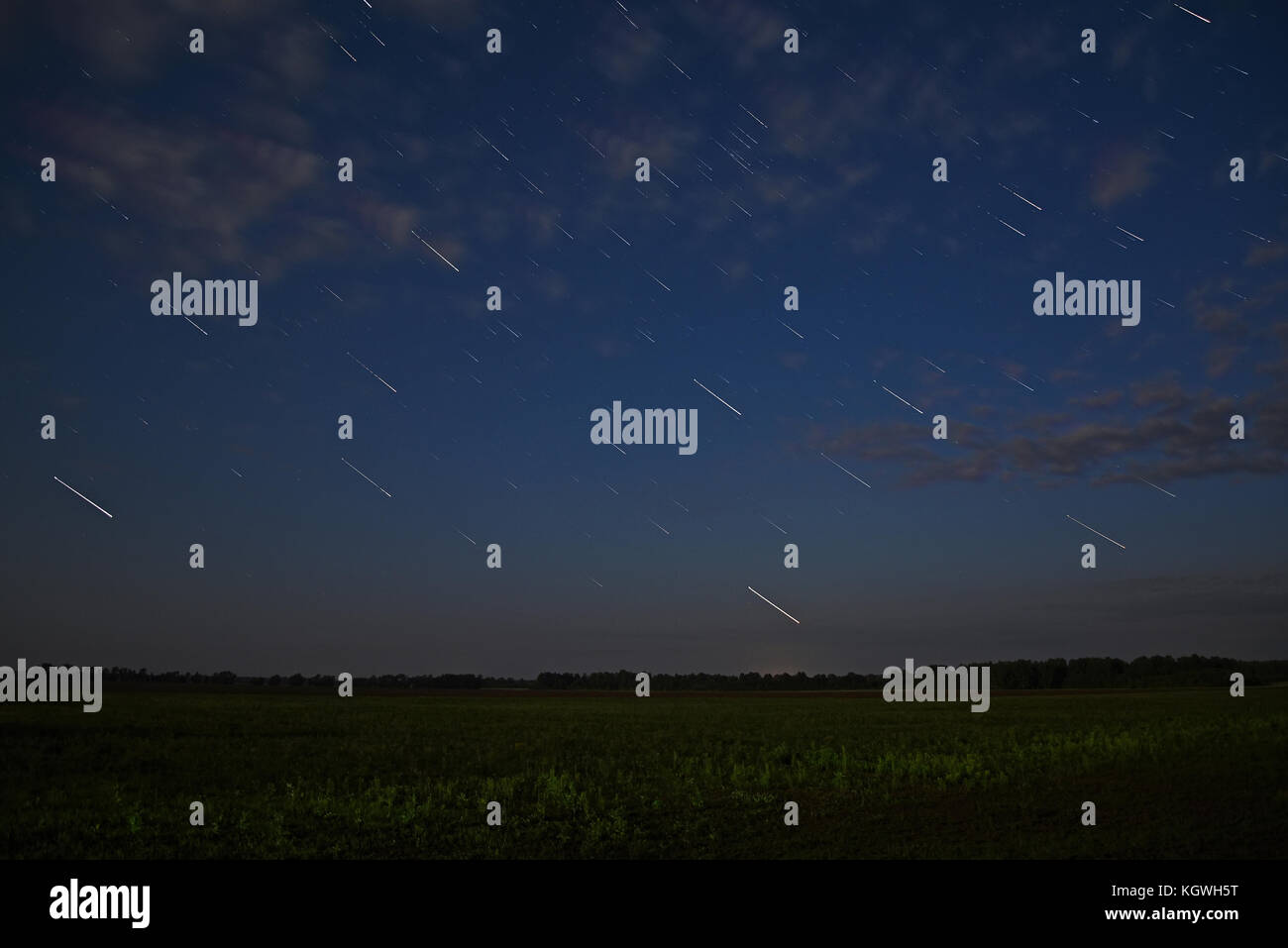 Malerische Nacht Landschaft mit Wolken und Sterne in der Form der Titel über die Felder und den Wald mit einer langen Belichtungszeit genommen Stockfoto