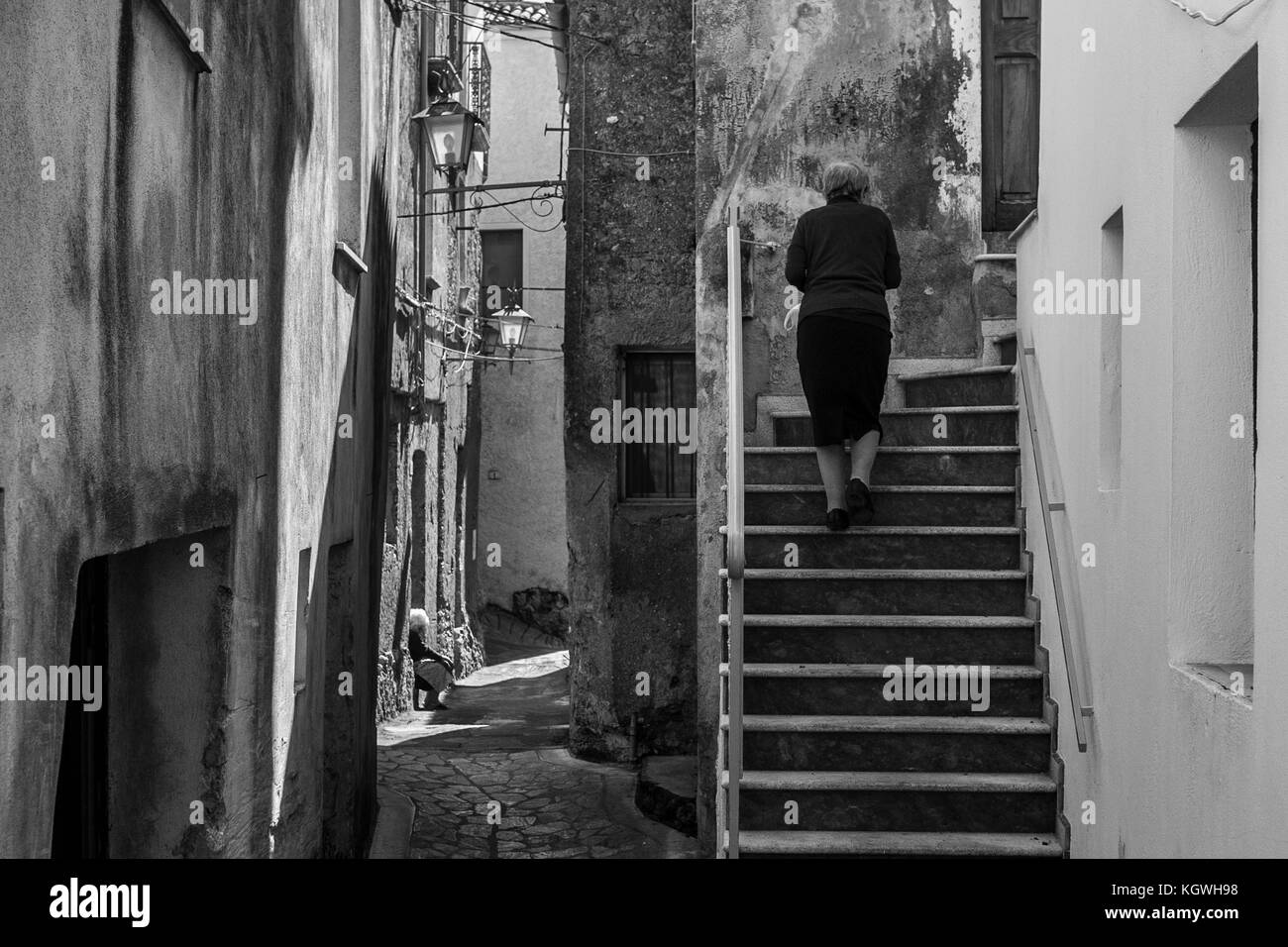 Eine alte Frau geht in die Straßen des Dorfes von aieta, Italien. aieta (auch in ajeta Form geschrieben) ist eine italienische Gemeinde von 814 Einwohnern in Stockfoto