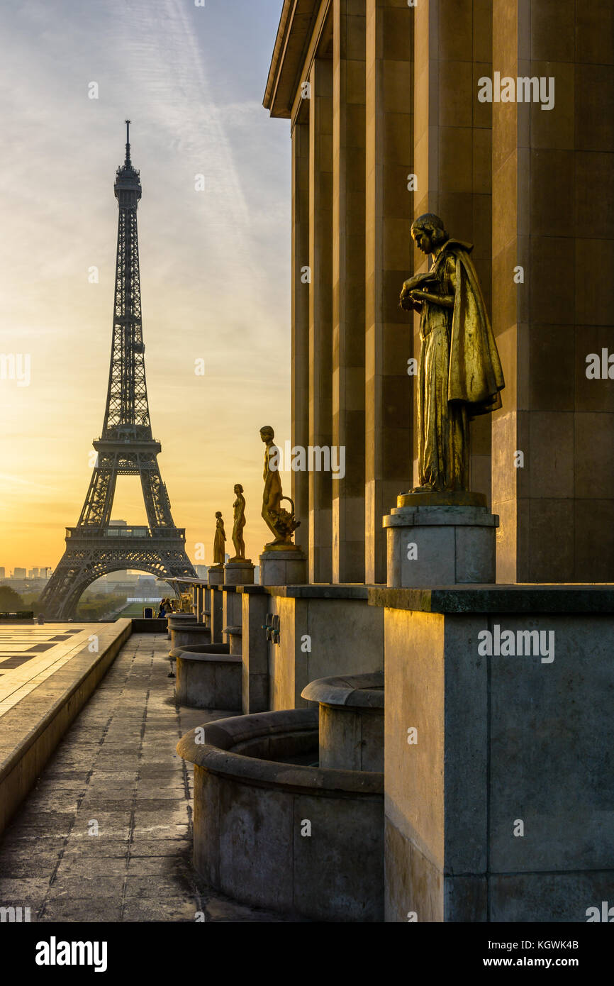 Die aufgehende Sonne beleuchtet die goldenen Statuen auf der Esplanade Trocadero und dem Eiffelturm sich gegen eine orange sky steht. Stockfoto