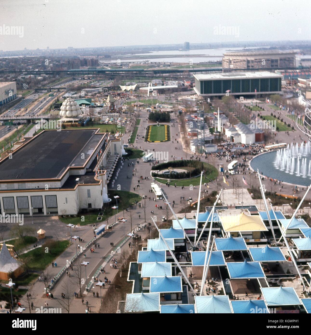 Panorama-Luftaufnahme nach Norden von den Aussichtstürmen des New York State Pavilion entlang der Avenue of the States, auf der New York World's Fair im Flushing Meadows Park, Corona, Queens, New York, Mai 1964. In der Ferne sieht man den Flughafen LaGuardia am Ufer der Flushing Bay, im Hintergrund das Shea Stadium. Oben rechts befindet sich das Gebäude des United States Pavilion am Fuße des Court of States. In der Mitte vertikal befindet sich die New Amsterdam Plaza mit dem New York City Pavilion Gebäude am linken Rand. Rechts sind die sechseckigen Gebäude des New England States Pavi Stockfoto