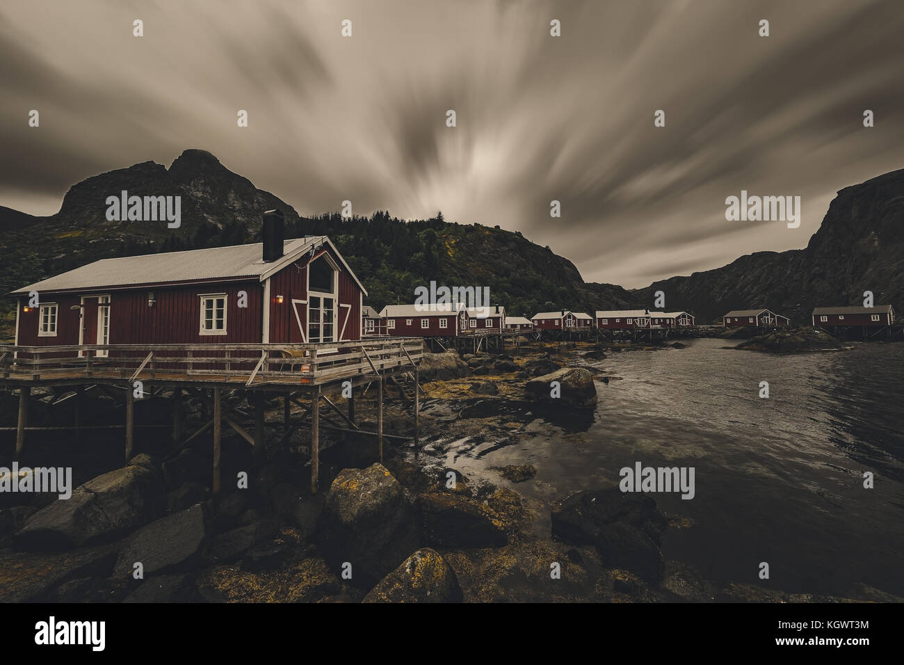 Traditionelle rote norwegische Fischerhaus mit die Berge und das Meer im Hintergrund in Nusfjord. Stockfoto