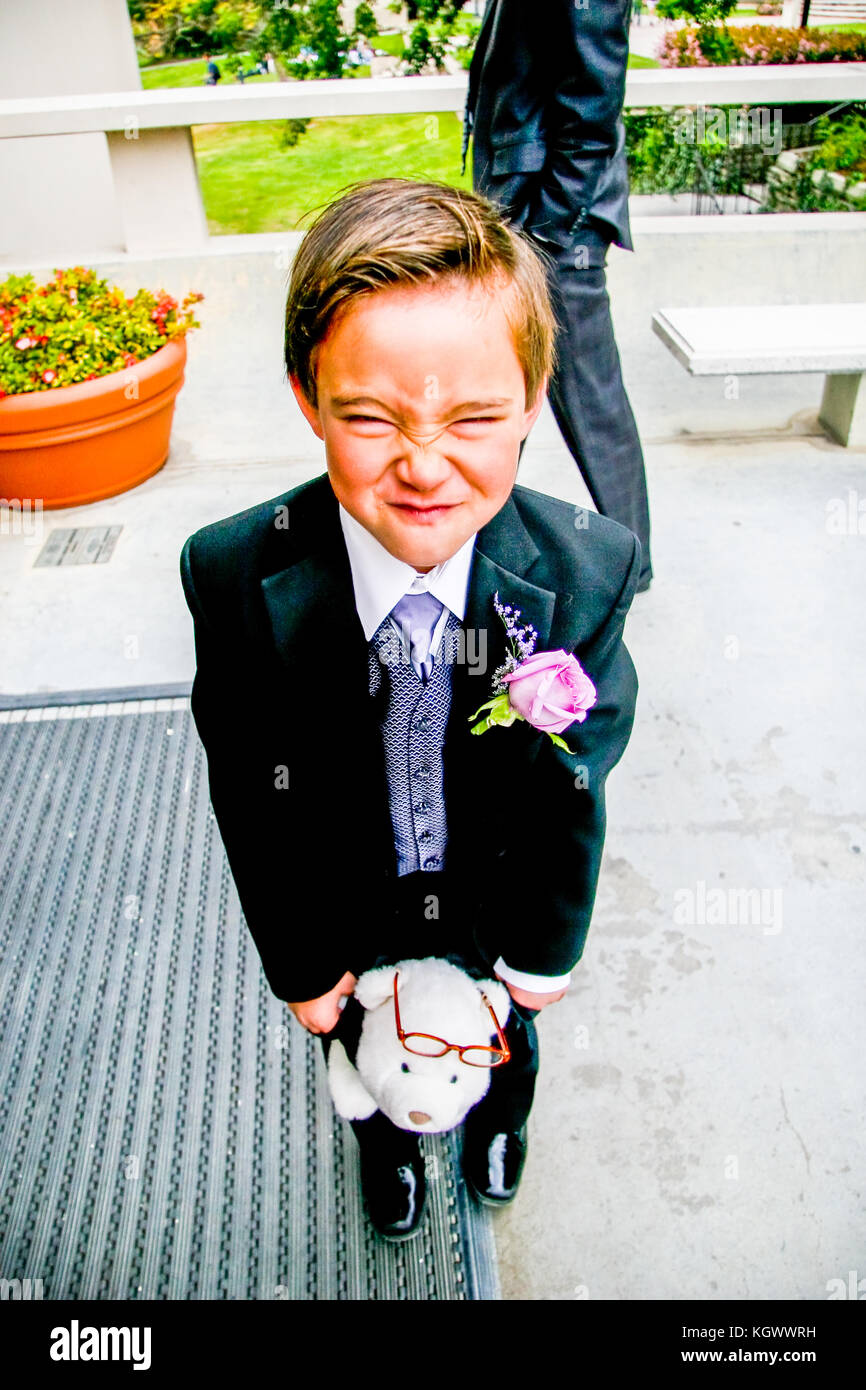 Eine junge Ring bearer Junge im Tuxedo, lustiges Gesicht vor der Trauung Stockfoto