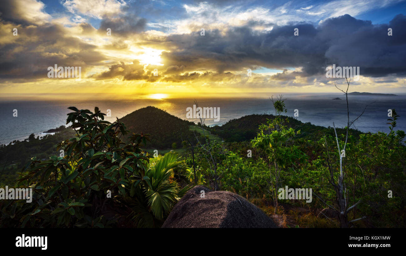 Sonnenuntergang hinter Wolken über zwei Hügel auf den Seychellen. Auf der Suche nach einem Berg. Stockfoto