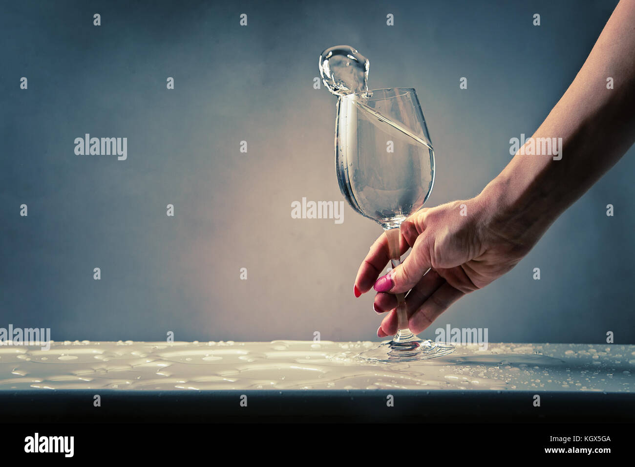 In der Nähe der weiblichen Hand mit einem Glas Wein mit Wasser gefüllt, auf nassen Tisch Stockfoto
