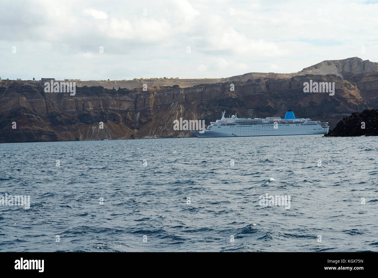 Kreuzfahrtschiff vor der Küste von Santorini an einem bewölkten Tag. Stockfoto