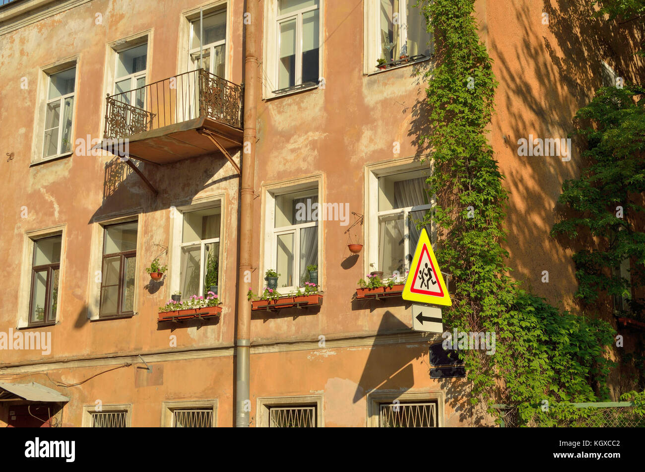 Alte Mauer eines Hauses hell erleuchtet von der Sonne an der Wand hängt ein Schild. Stockfoto
