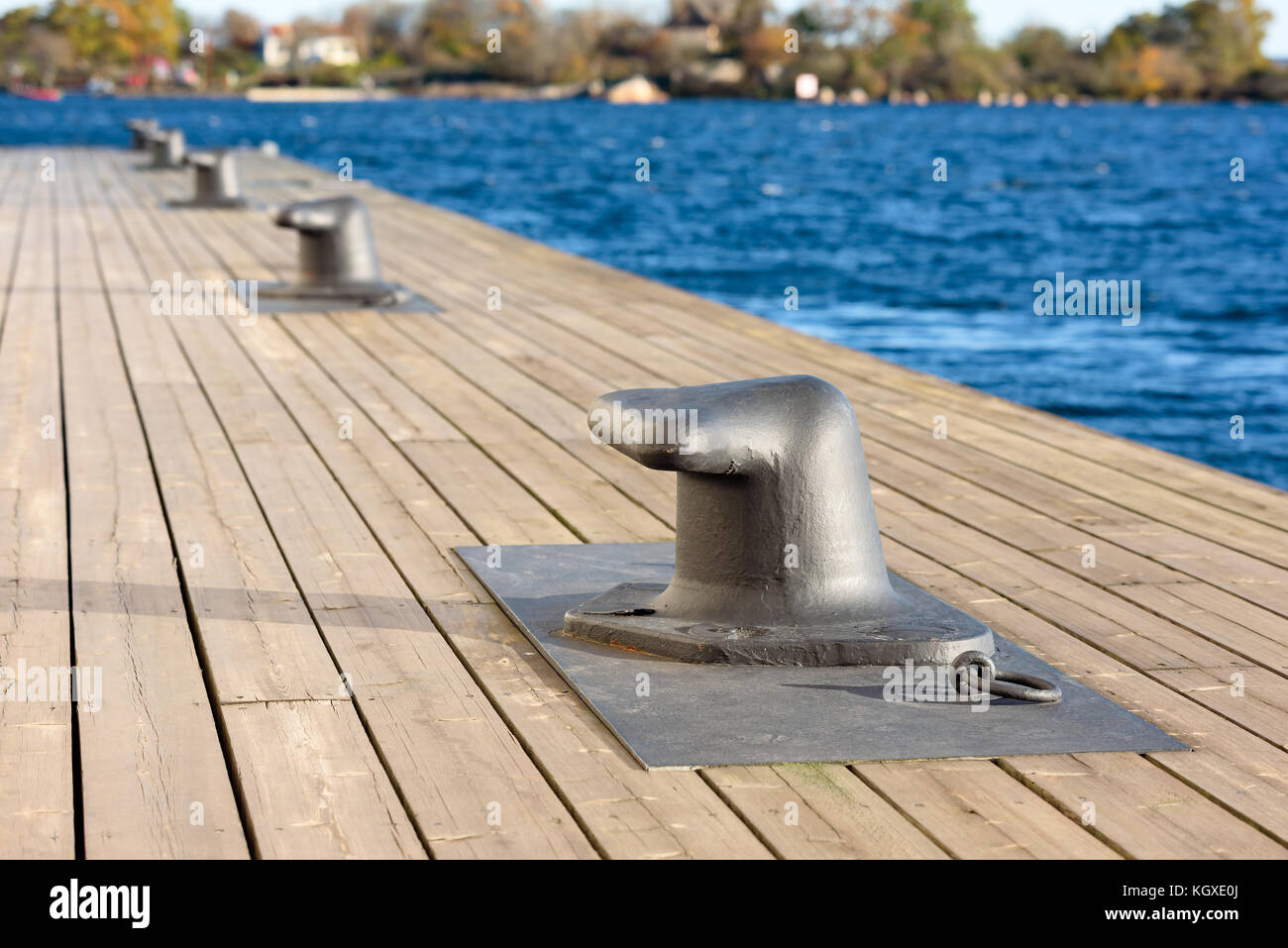 Bügeleisen Poller auf hölzernen Pier mit Küstenlandschaft im Hintergrund verschwommen. Stockfoto