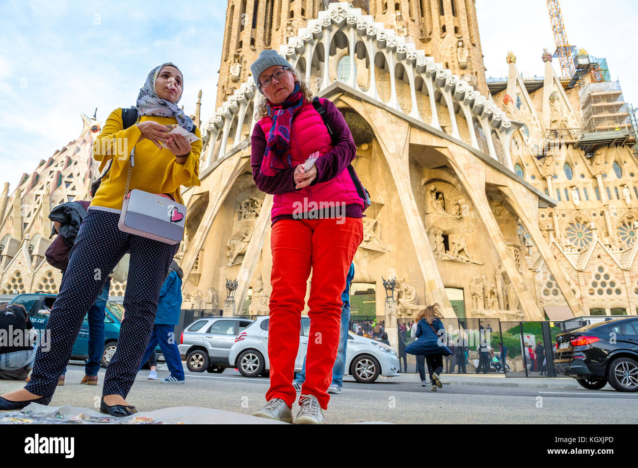 Weibliche Touristen den Kauf von Souvenirs aus einer Straße Händler außerhalb der Sagrada Familia, Barcelona. Stockfoto