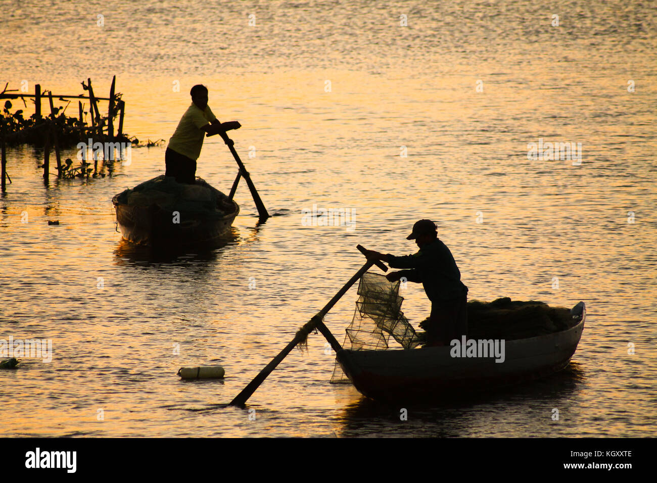 Silhouetten der Fischer ihre Netze gegen den Sonnenuntergang absenken Stockfoto