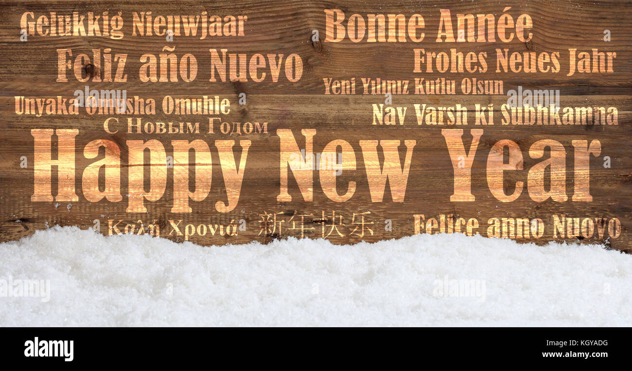 Ein frohes neues Jahr wünschen in vielen Sprachen auf verschneiten Holz- Hintergrund Stockfoto