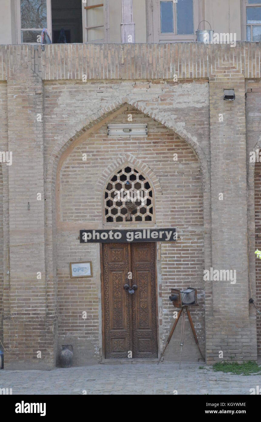Eine altmodische Kamera auf Stativ stand vor einer Fotogalerie in Buchara, Usbekistan. alte Holztür mit islamischen Muster geschnitzt ist gesperrt. Stockfoto