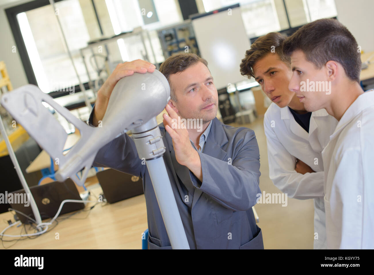 Techniker mit dem Modell von Flugzeugen Schwanz und zwei Studenten Stockfoto
