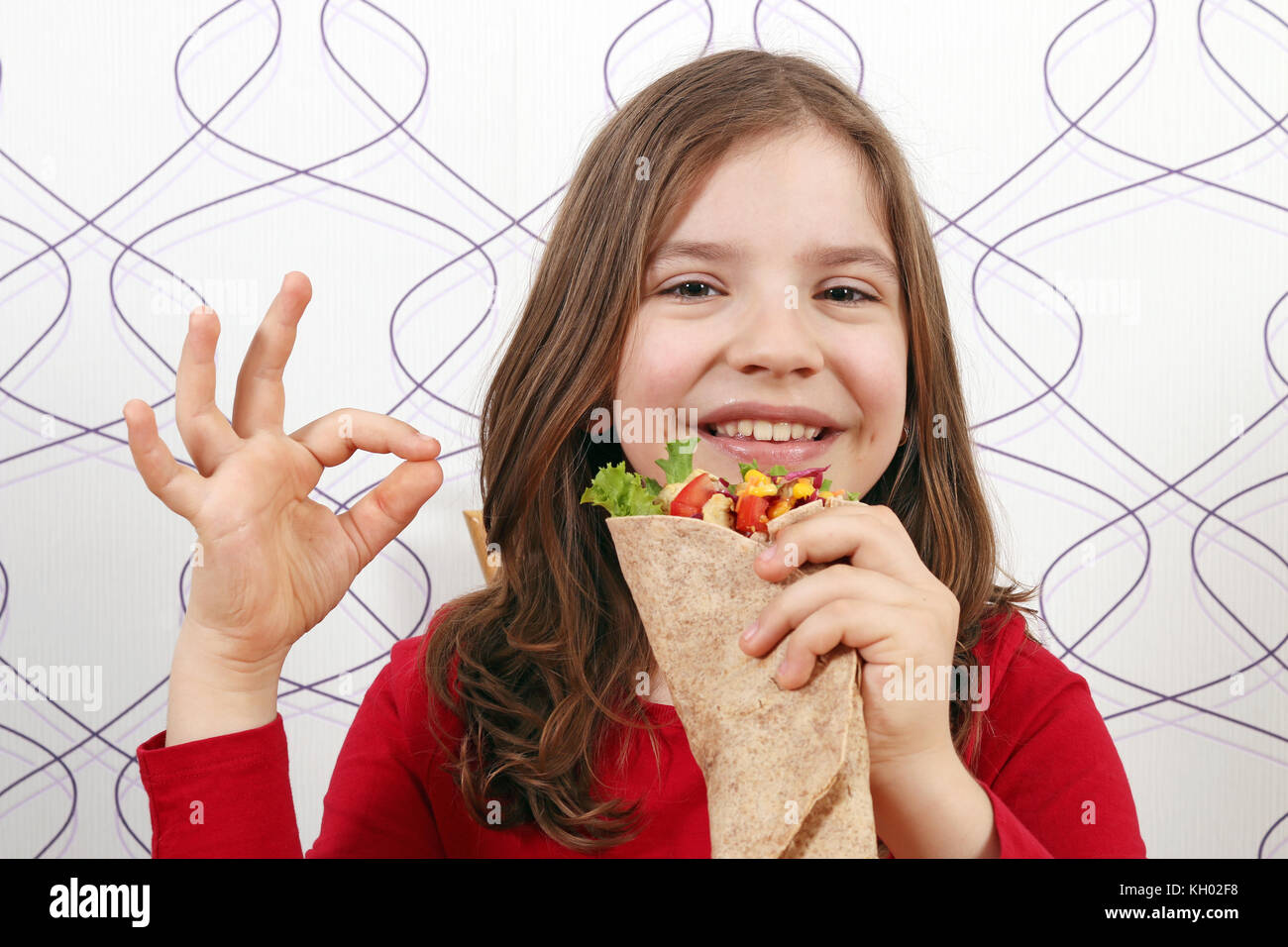 Glückliche kleine Mädchen mit Burritos und ok Handzeichen Stockfoto