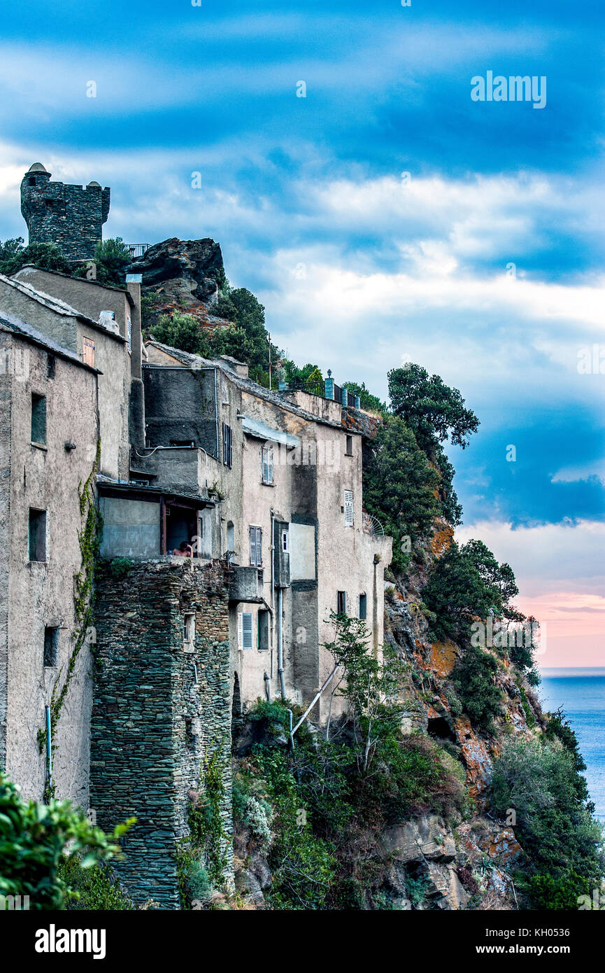 Europa. Frankreich. Korsika. Cap Corse. Die alten Häuser des Dorfes hängen bei Sonnenuntergang an der Klippe Stockfoto