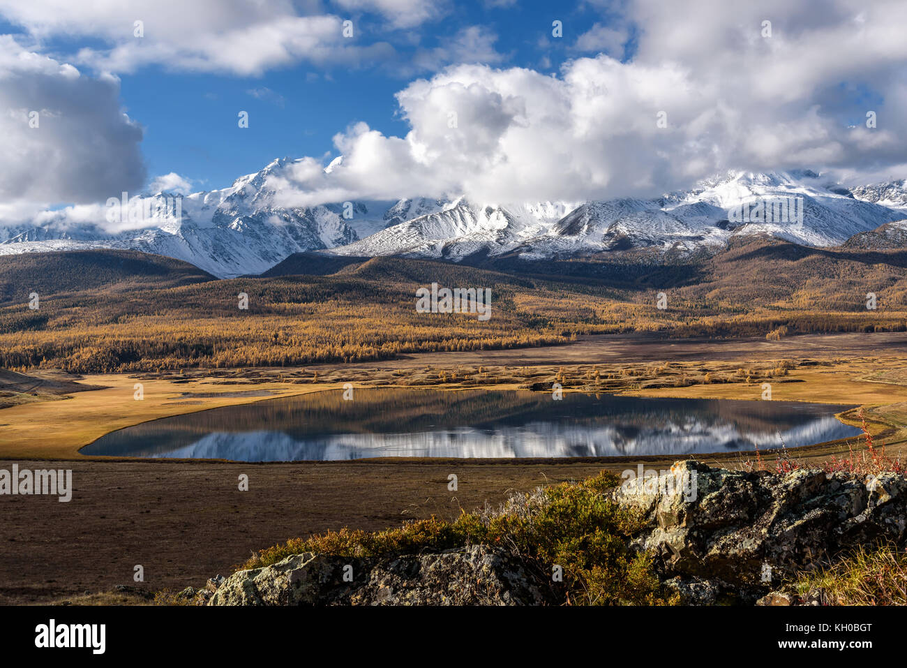 Helle malerischen Herbst Landschaft mit schönen See in der Steppe, schneebedeckte Berge und ihre Reflexion auf dem Hintergrund des blauen Himmels und Clo Stockfoto