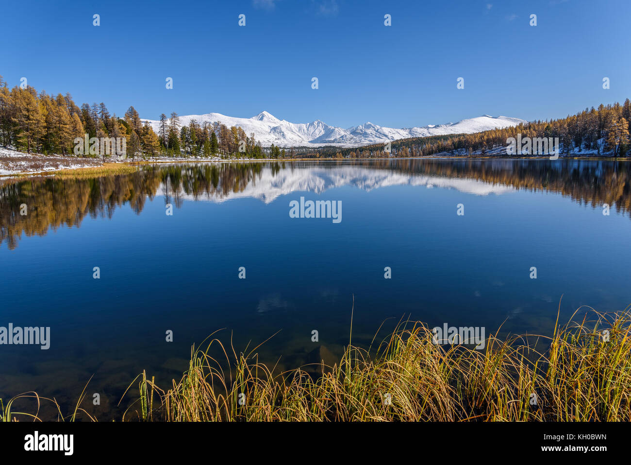 Helle malerischen Herbst Landschaft mit einem wunderschönen See, Wald, schneebedeckte Berge und ihre Überlegungen auf dem Hintergrund der blauen Himmel an einem sonnigen Stockfoto