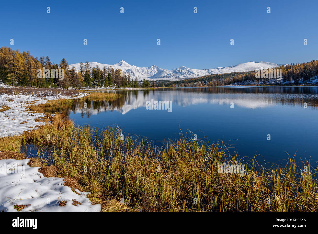 Helle malerischen Herbst Landschaft mit einem wunderschönen See, Wald, schneebedeckte Berge und ihre Überlegungen auf dem Hintergrund der blauen Himmel an einem sonnigen Stockfoto