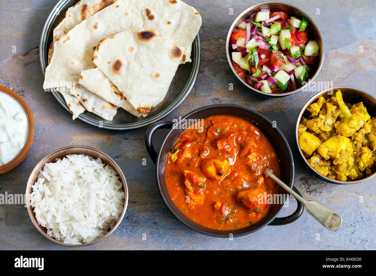 Indisches essen mit Chicken Tikka Masala, Aloo Gobi, Salat, Reis und Brot Stockfoto
