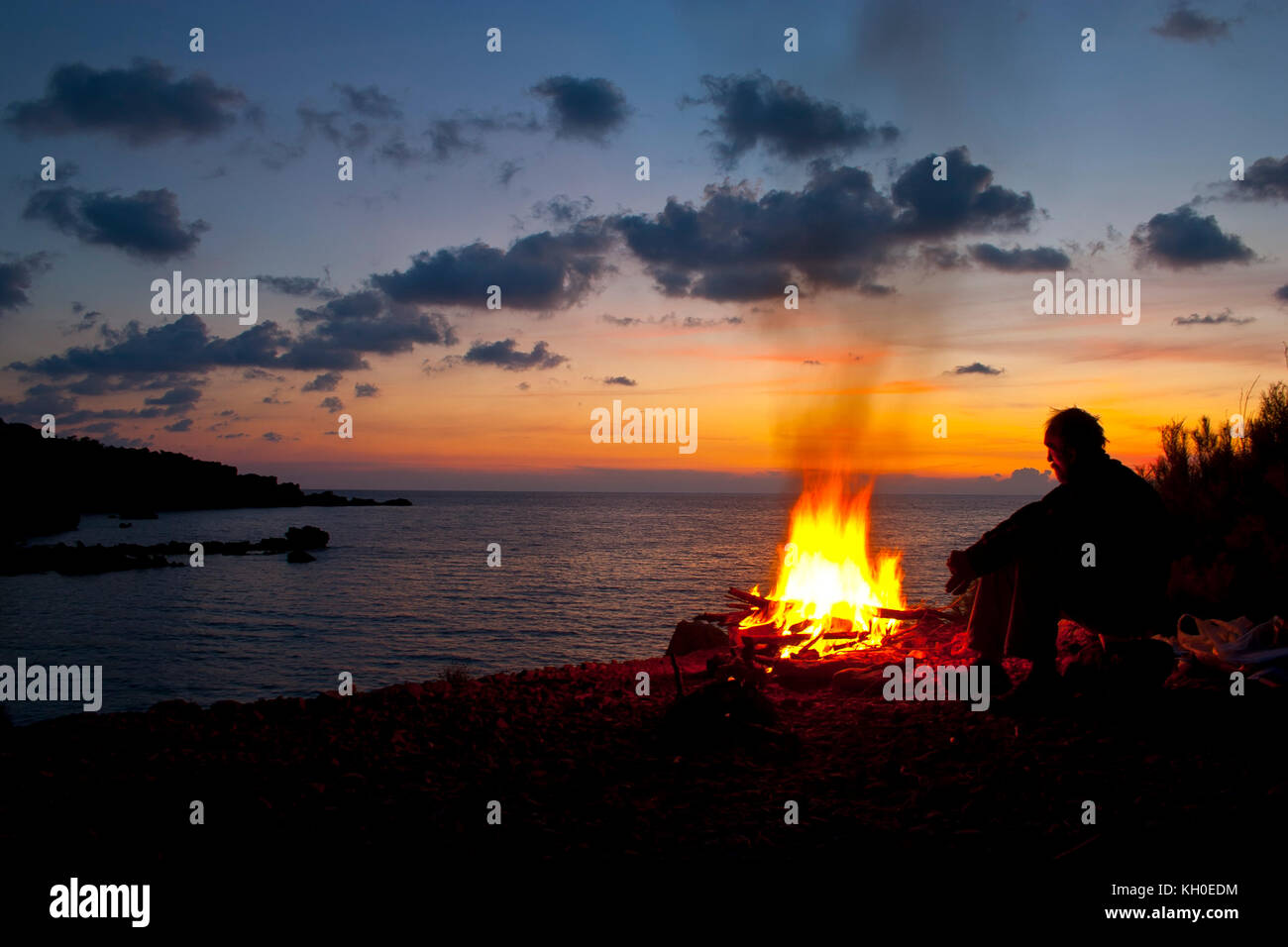 Mann sitzt am Feuer Stockfoto
