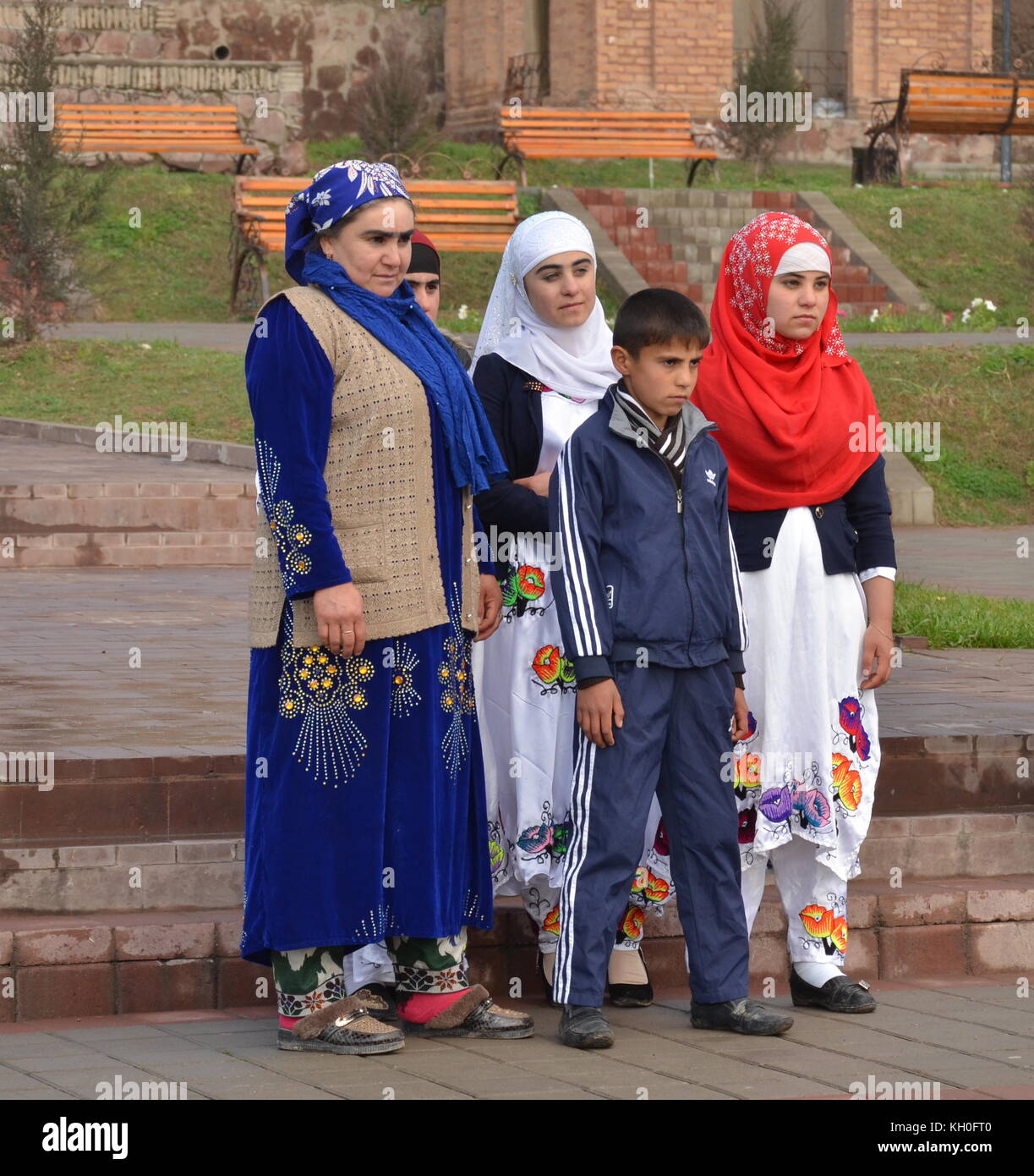 4 Frauen mit Kopftuch und einen Sohn posieren für ein Foto mit traditioneller Kleidung in Tadschikistan. Stockfoto