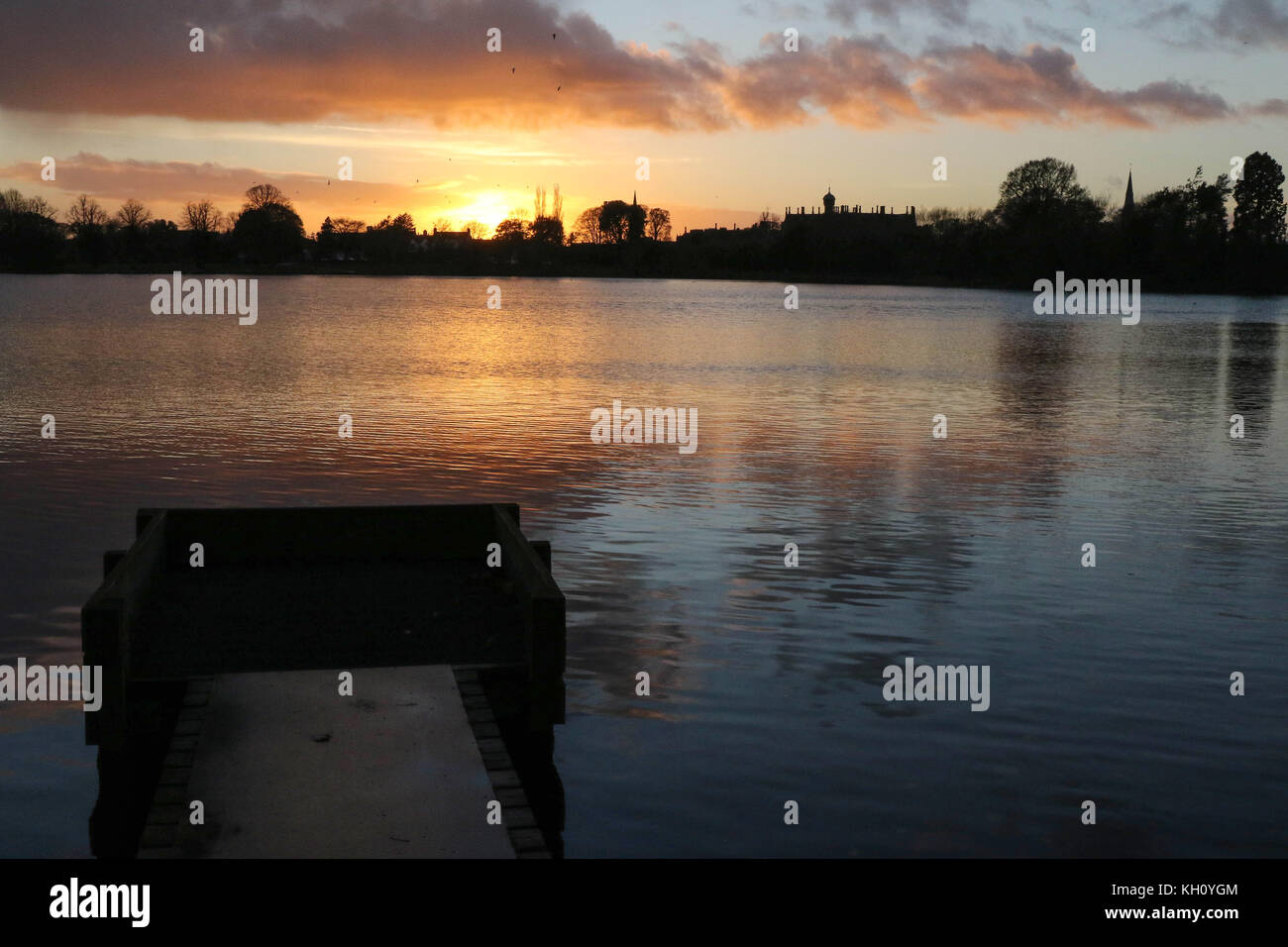 Lurgan Park See, Nordirland, Großbritannien. 12. November 2017. Ein blustery Tag mit kalten Nord-westlichen Winden und Duschen endet mit Clearing Skies und fallende Temperaturen. Frost zu rechnen ist, möglicherweise als niedrig zu-4C in ländlichen Gebieten, wie die Sonne auf der linken Seite von Shankill Pfarrkirche und Brownlow House (rechts). Quelle: David Hunter/Alamy Leben Nachrichten. Stockfoto