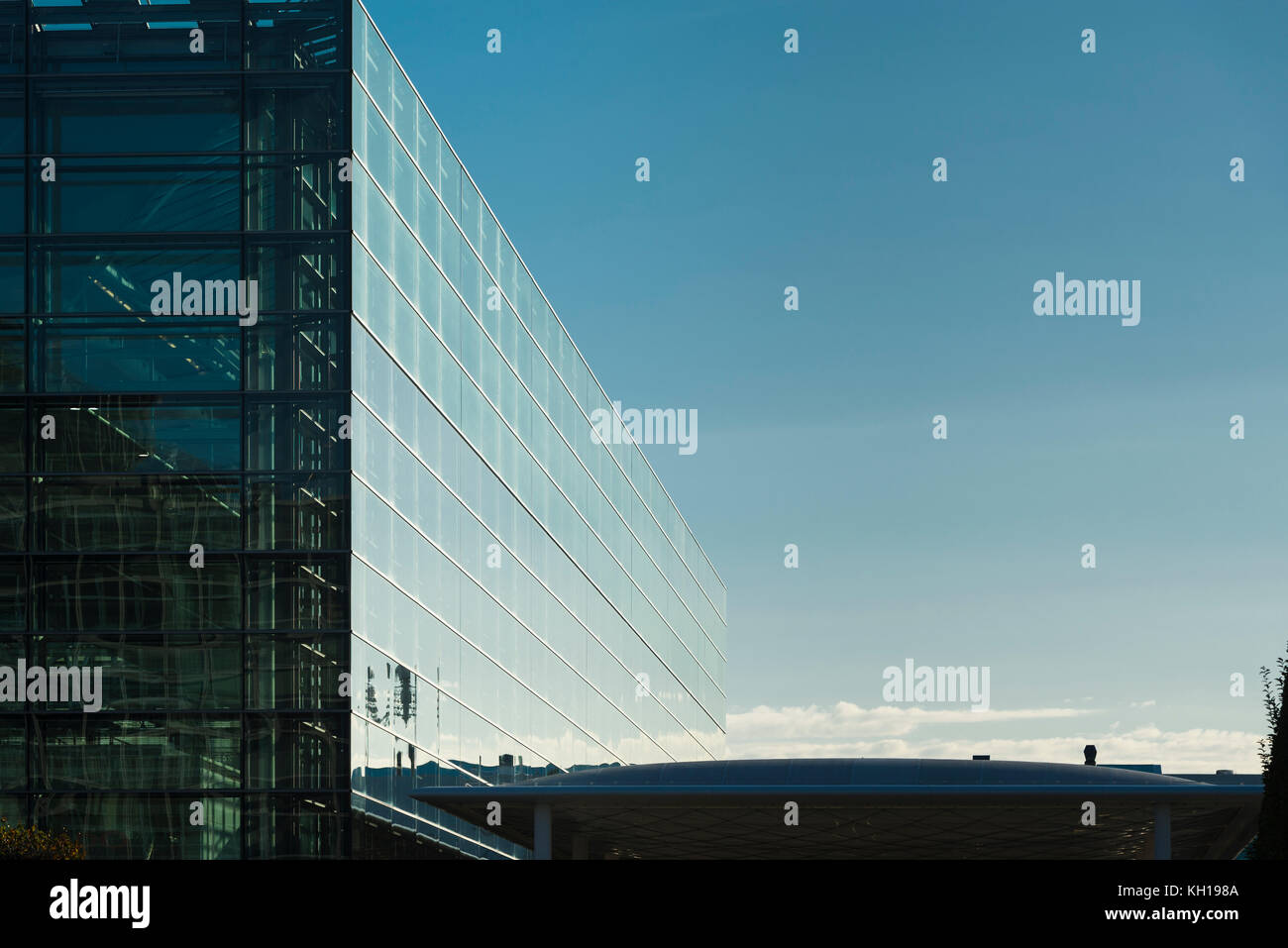 Glasfassade des Terminals 2 Gebäude des Flughafens München muc in der Morgensonne vor blauem Himmel, Bayern, Deutschland Stockfoto