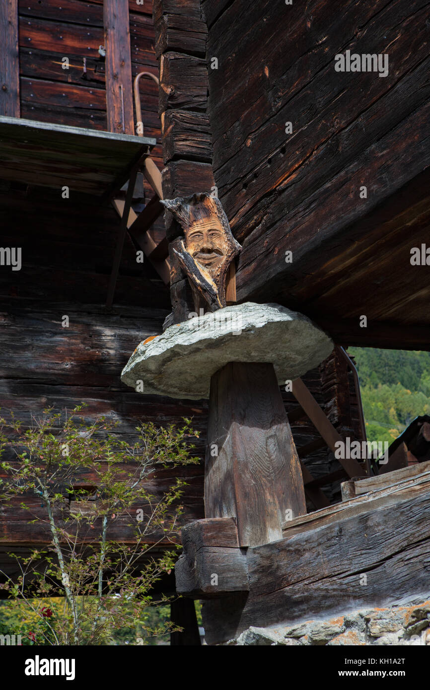 BLATTEN, SCHWEIZ - SEPT. 28, 2017: Schädlingsbekämpfung: Staddle oder steddle Steine unter einem traditionellen Schweizer Chalet mit einem Holz geschnitzt Gesicht, eine lokale tradi Stockfoto