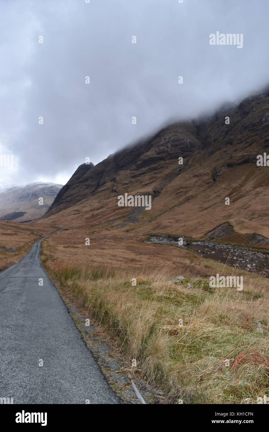 Einspurige Straße und Hügel, die von tief liegenden Wolken in Glen Etive, in der Nähe von Glencoe, Schottland, gespeist werden. Stockfoto