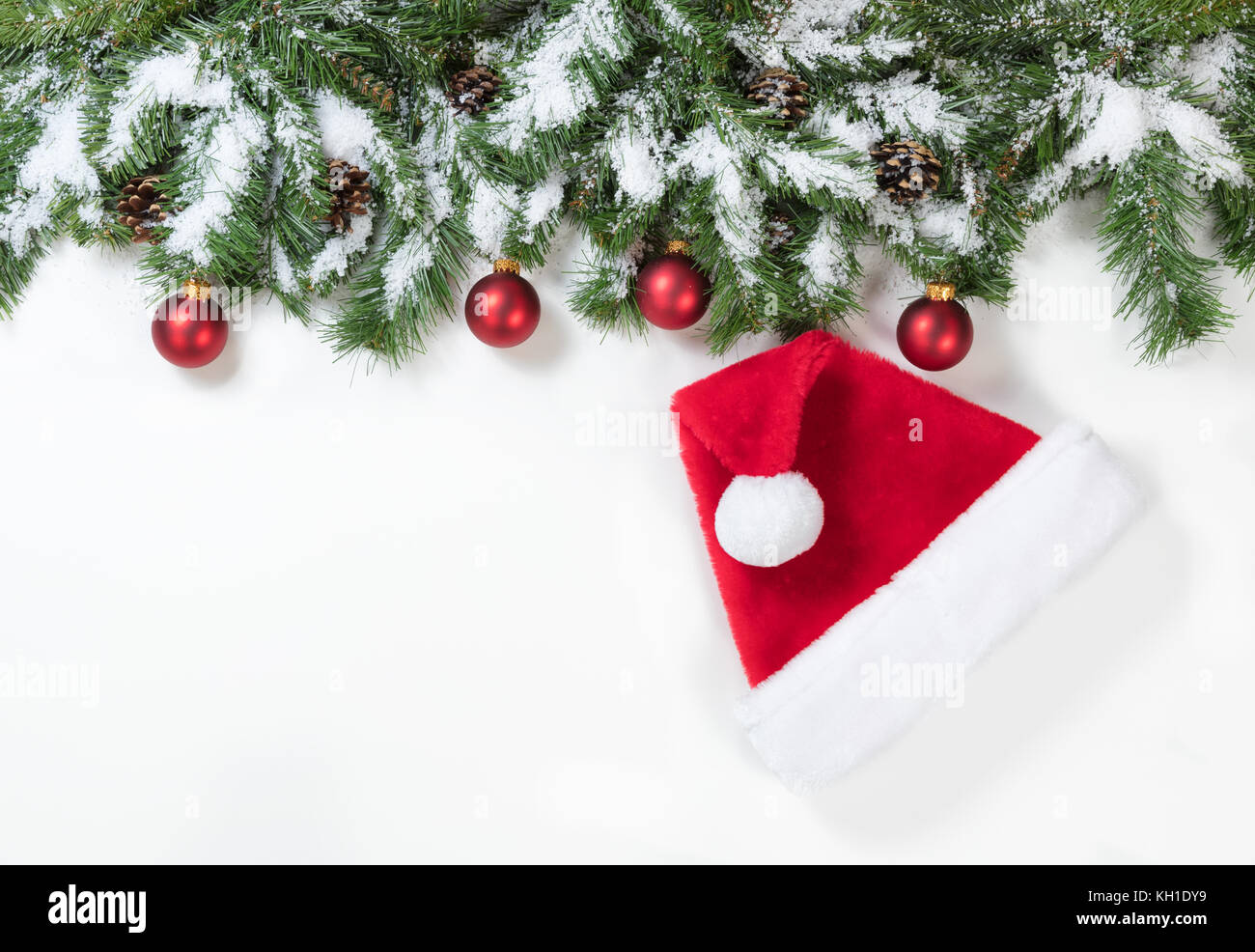 Weihnachten schneebedeckten Ästen, rote Verzierungen und Santa Claus hat auf weißem Hintergrund Stockfoto