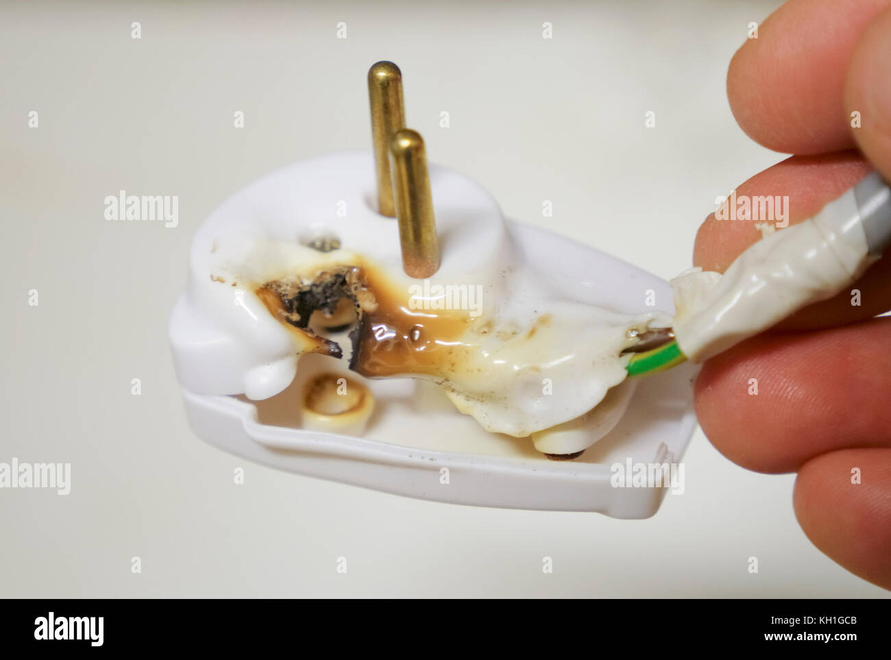 Nahaufnahme einer Hand, die eine verbrannte Stecker mit Kunststoff, die