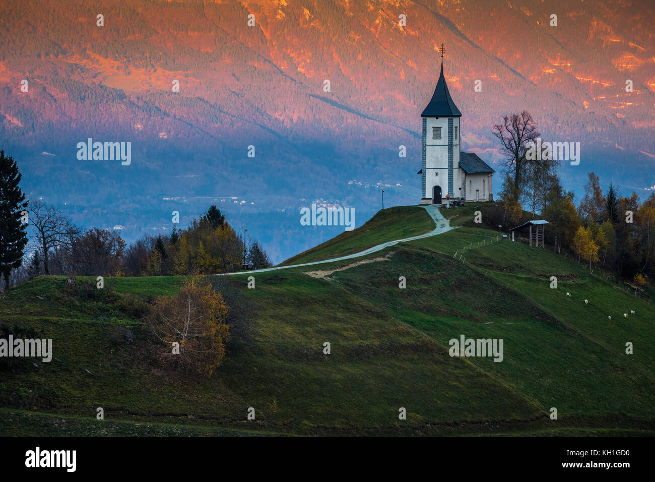 Jamnik, Slowenien - Schöner goldener Sonnenuntergang in der Jamnik St. Primoz Kirche. Julian Alpen im Hintergrund Stockfoto