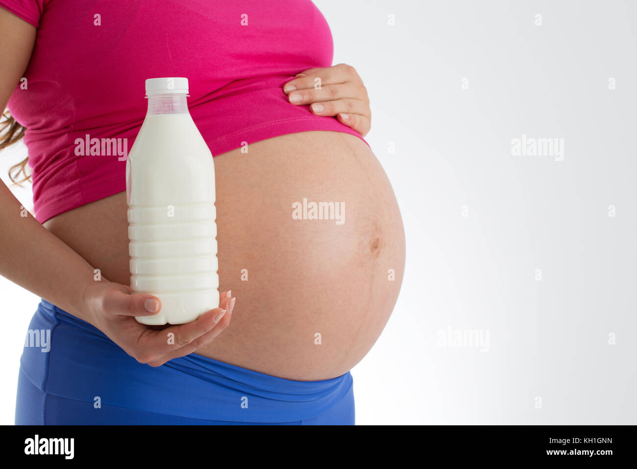 Schwangerschaft und gesundes Menü - schwangere Frau mit Milch Flasche auf weißem Hintergrund Stockfoto