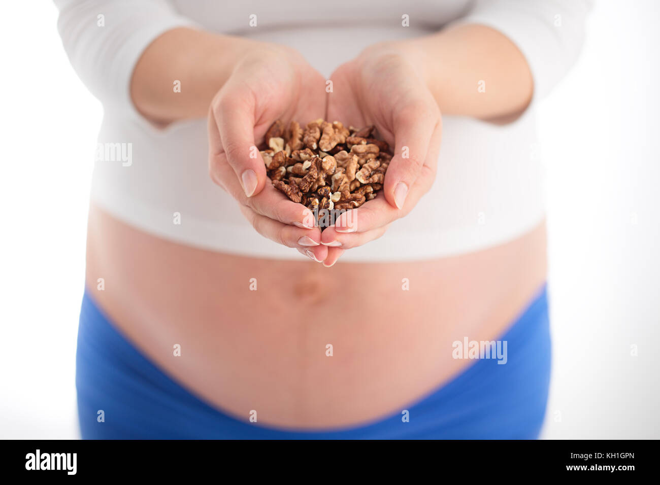 Schwangerschaft und gesundes Menü Konzept. Schwangere Frau mit Walnüsse in seine Hände, auf weißem Hintergrund Stockfoto