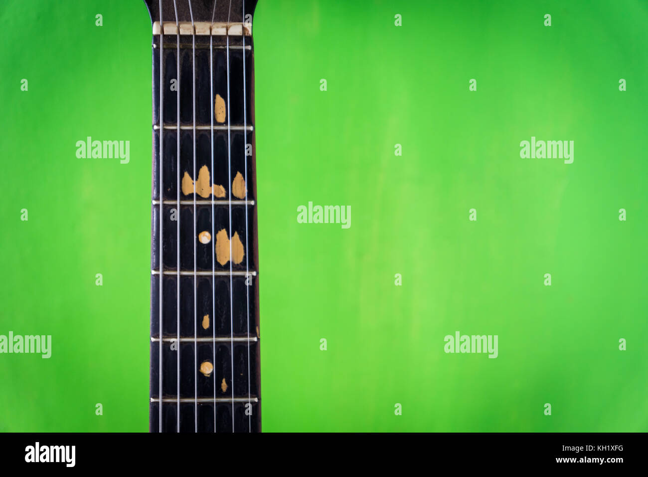 Alte akustische Gitarre auf grüne Farbe Wand Hintergrund - vintage grunge Stil mit abgebrochenen Griffbrett Stockfoto