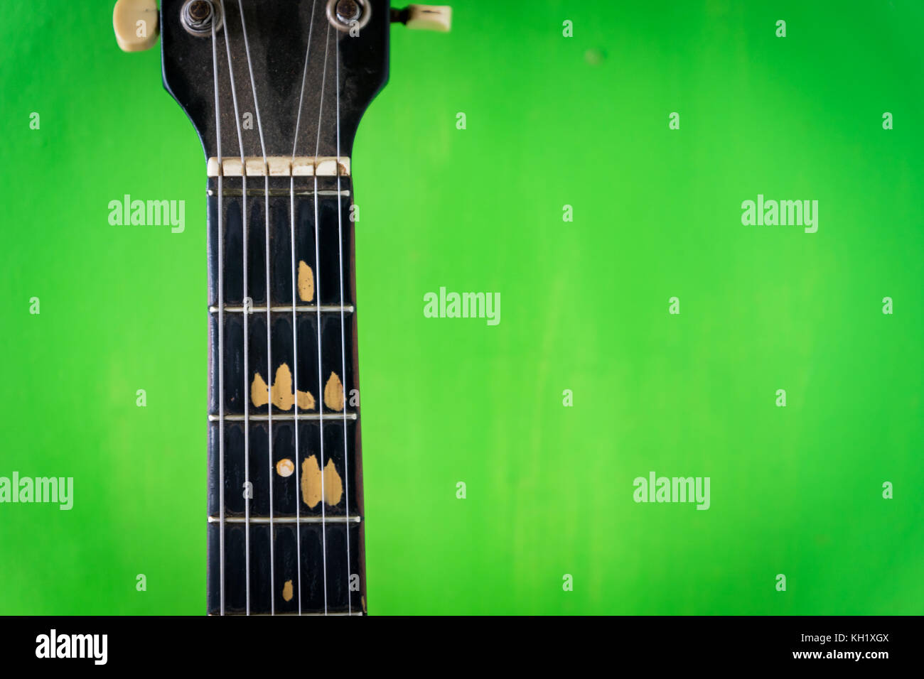 Alte akustische Gitarre auf grüne Farbe Wand Hintergrund - vintage grunge Stil mit abgebrochenen Griffbrett Stockfoto