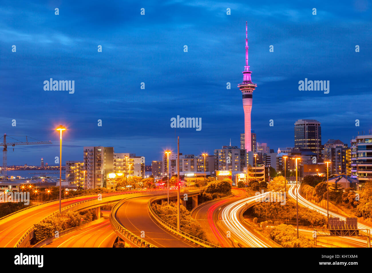 Auckland Motorway und Auckland Skyline, beleuchtet in der Dämmerung und mit Pfaden für Autoscheinwerfer. Stockfoto