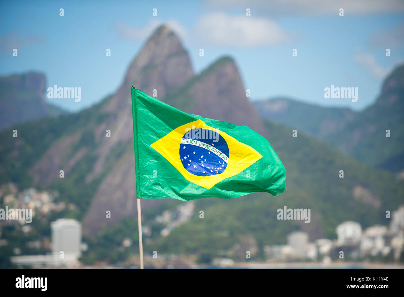 Brasilianische Flagge im Wind vor dem Two Brothers Mountain am Ipanema Beach in Rio de Janeiro. Stockfoto