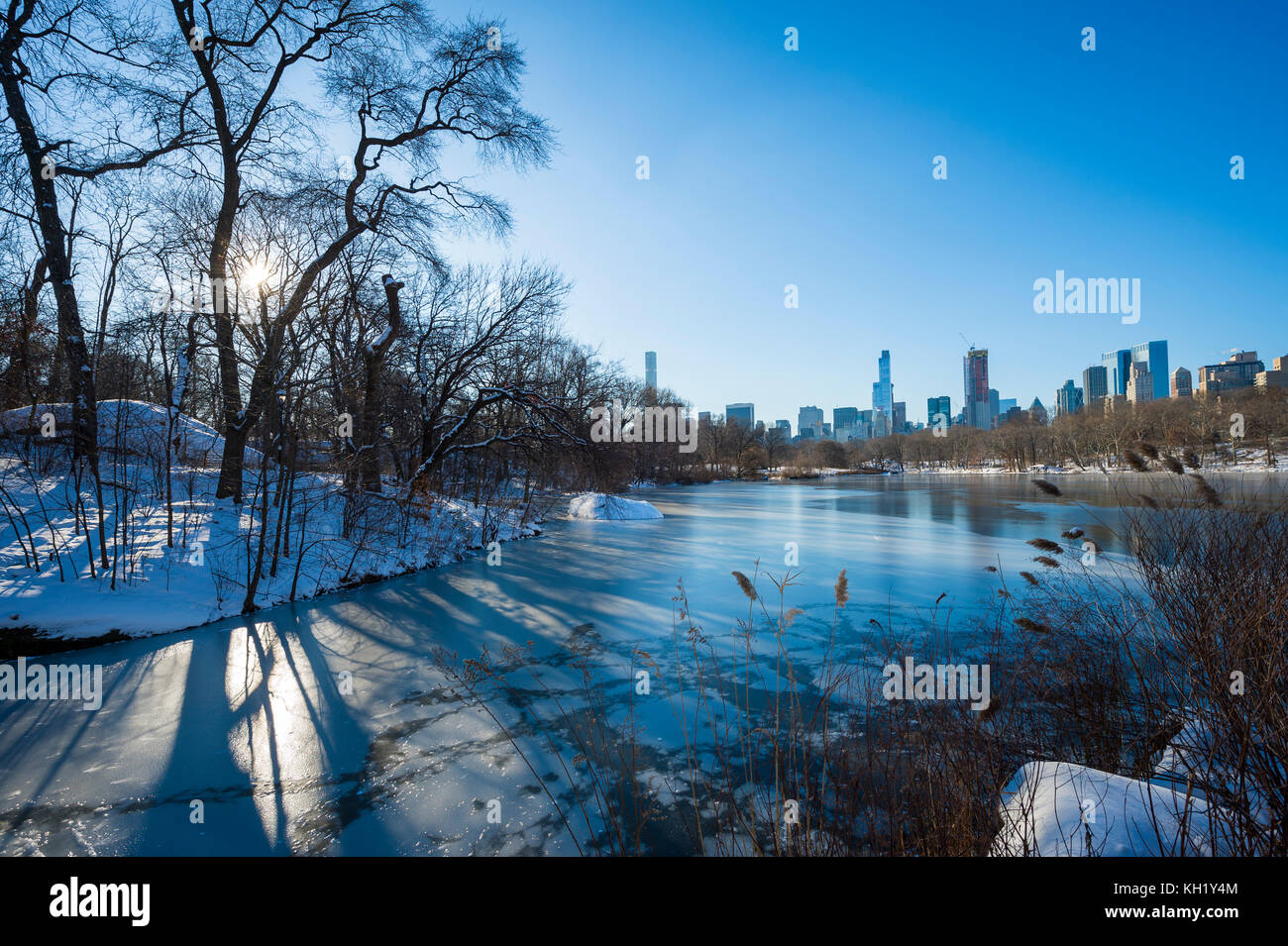 Malerische Aussicht auf die Skyline von Midtown in das Eis des zugefrorenen Central Park See spiegelt die Morgen nach einem Winter Schnee Sturm in new york city Stockfoto