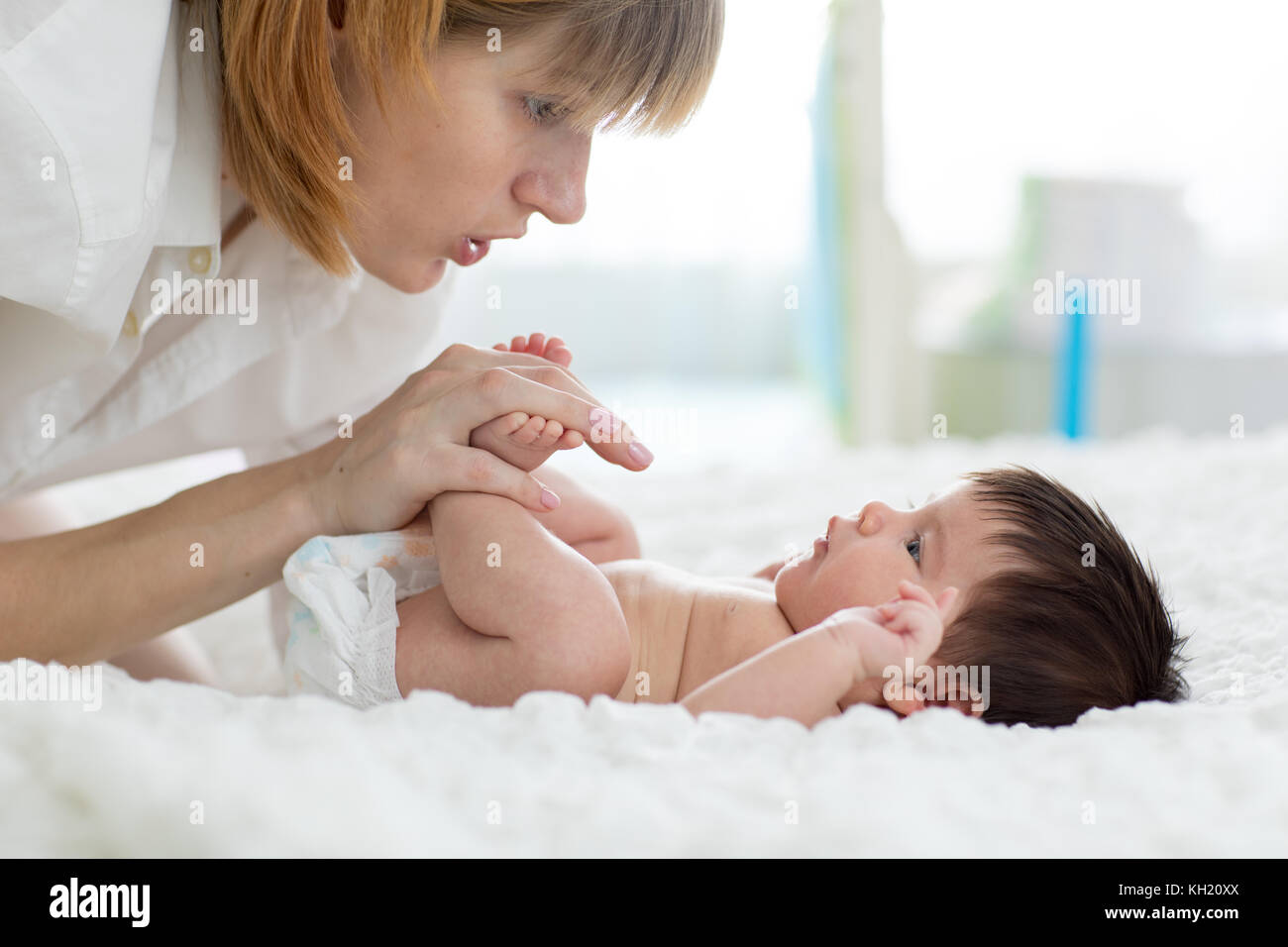 Mutter sanft massieren die Füße Ihres Babys Stockfoto
