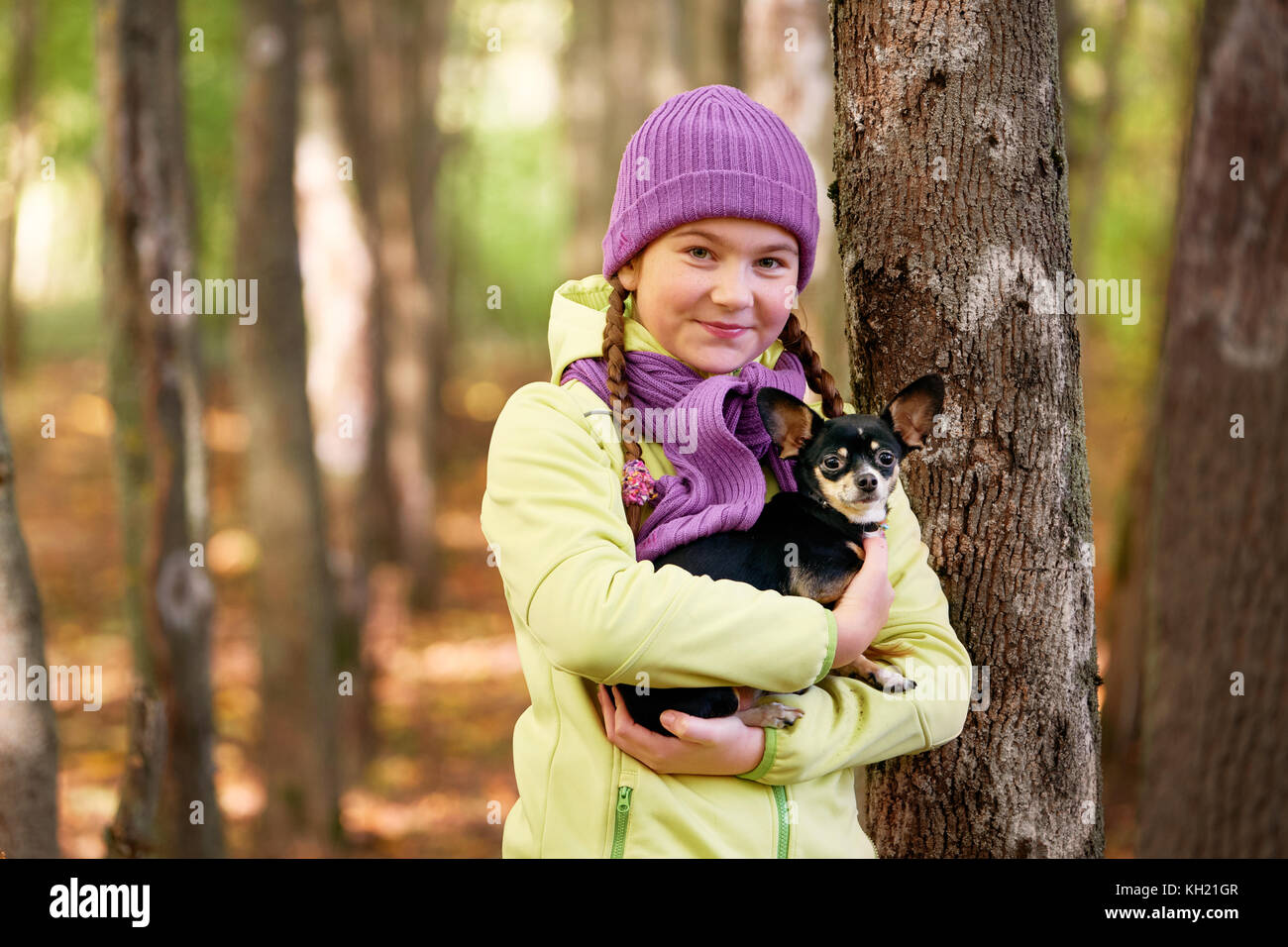 Baby Mädchen im Freien mit einem kleinen Hund. lächelnd Jugendmädchen entspannen mit Hund. cute Teen Girl trägt eine Jacke und lila Hut, Wandern mit ihrem Chihuahua Stockfoto