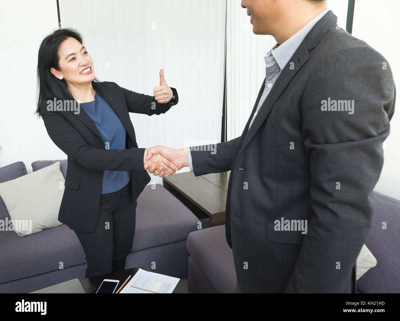 Lächeln Business-frau und Geschäftsmann zitternden Hand und Daumen hoch, im Büro, im Partnerschaftsabkommen Konzept, gute Lösungen. Stockfoto