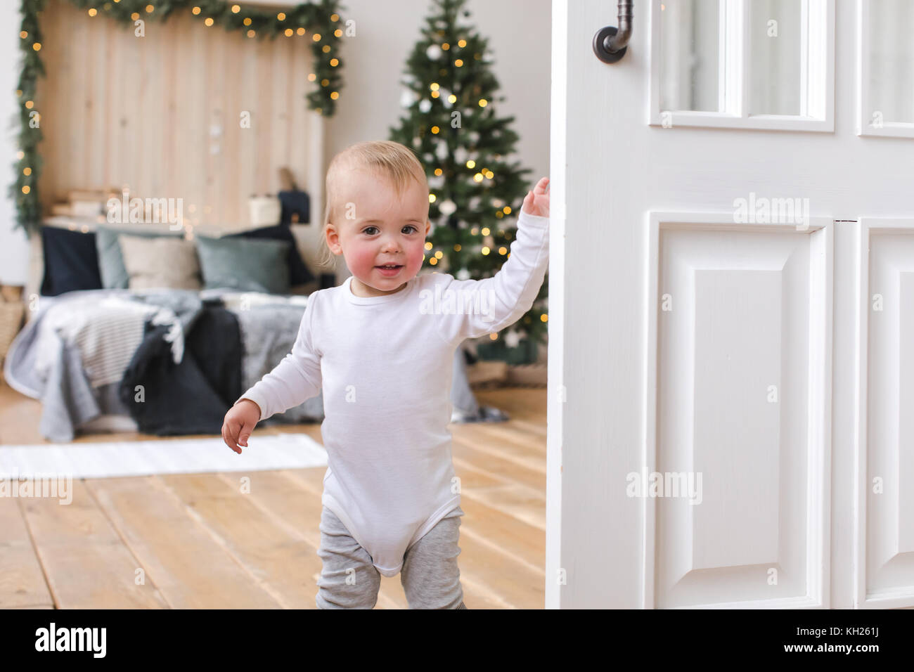 Niedliches Kleinkind im Schlafzimmer mit Weihnachtsbaum Stockfoto
